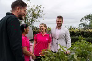Josh, Ed and two nurses discussing by a flower bed or vegetable garden smiling 3